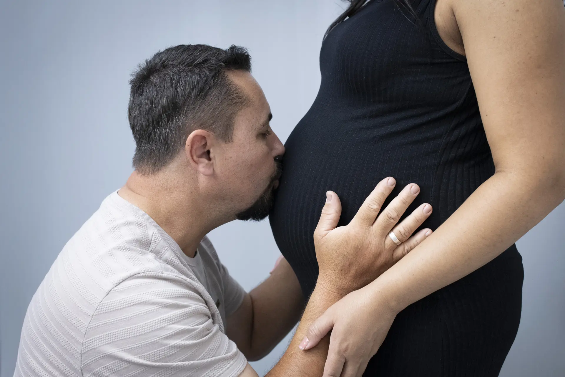 Detalhe de beijo na barriga durante ensaio gestante